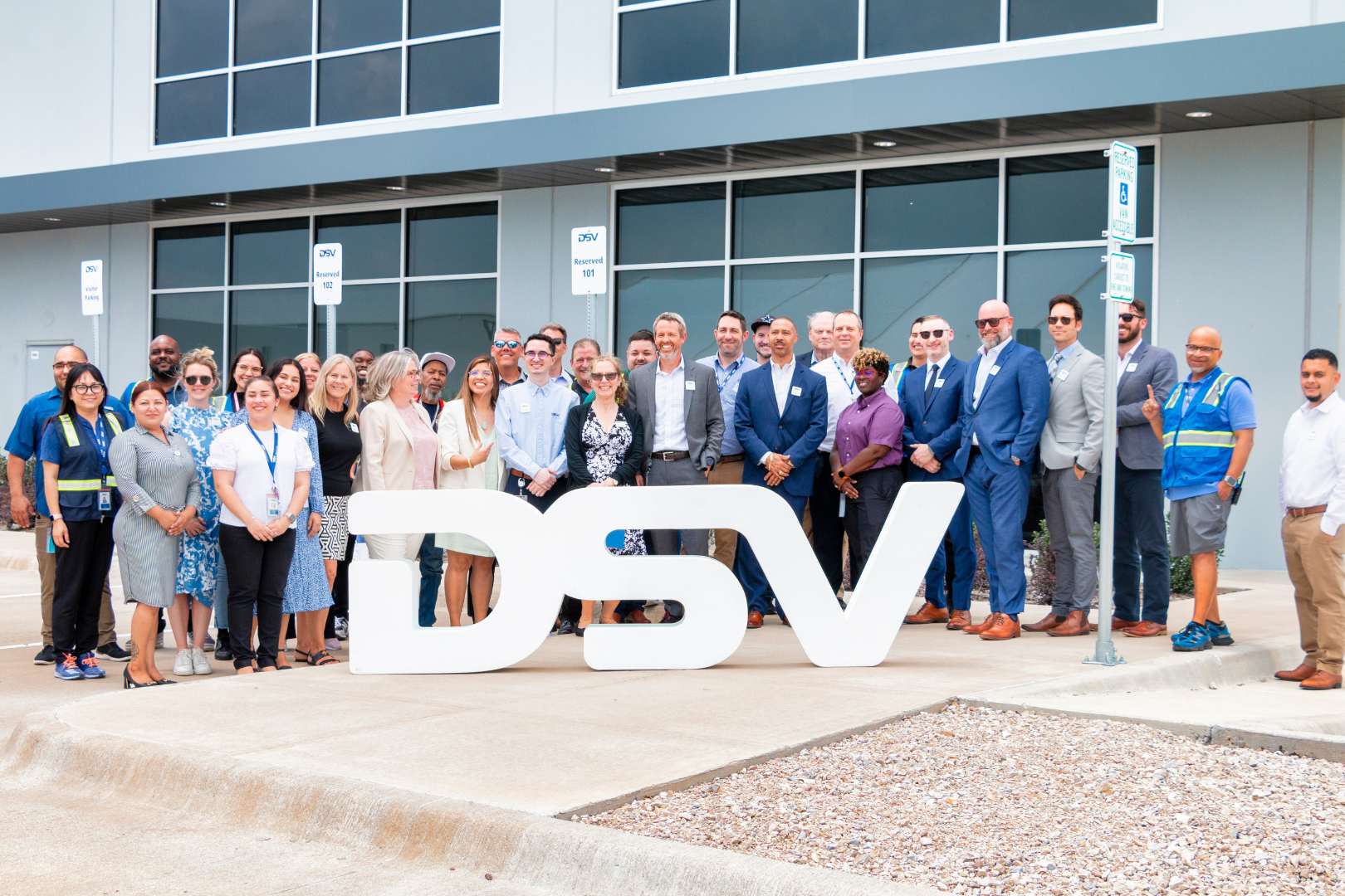 DSV Staff posing behind DSV logo
